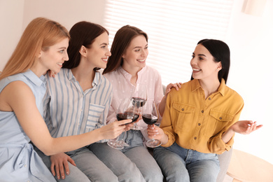 Photo of Beautiful young ladies clinking glasses of wine at home. Women's Day