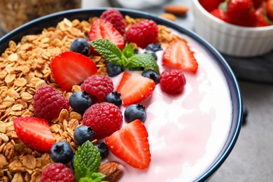 Photo of Tasty homemade granola with yogurt on grey table, closeup. Healthy breakfast