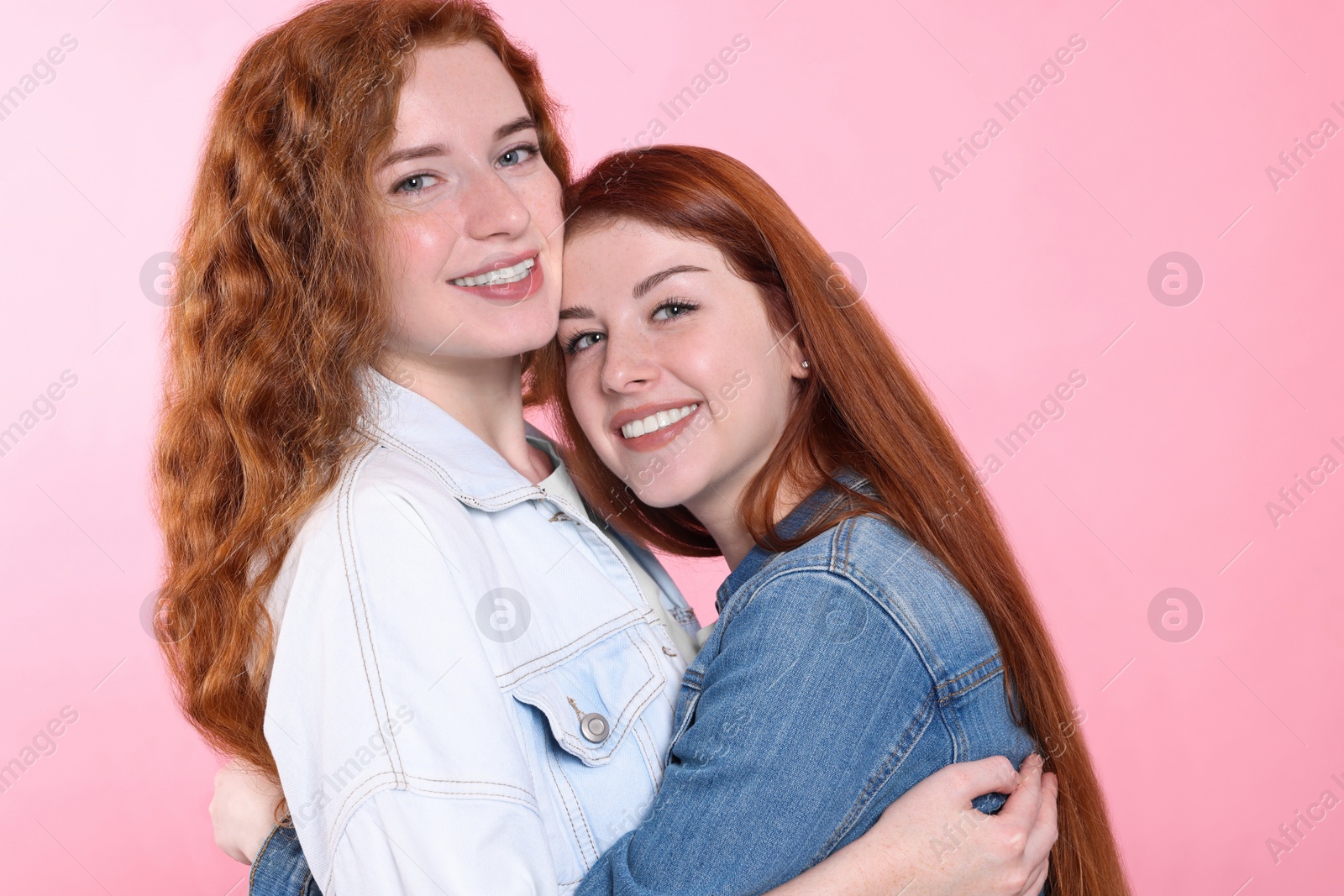 Photo of Portrait of beautiful young redhead sisters on pink background