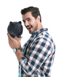 Handsome young man with piggy bank on white background