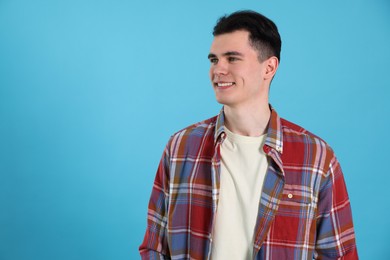 Portrait of handsome young man on light blue background, space for text