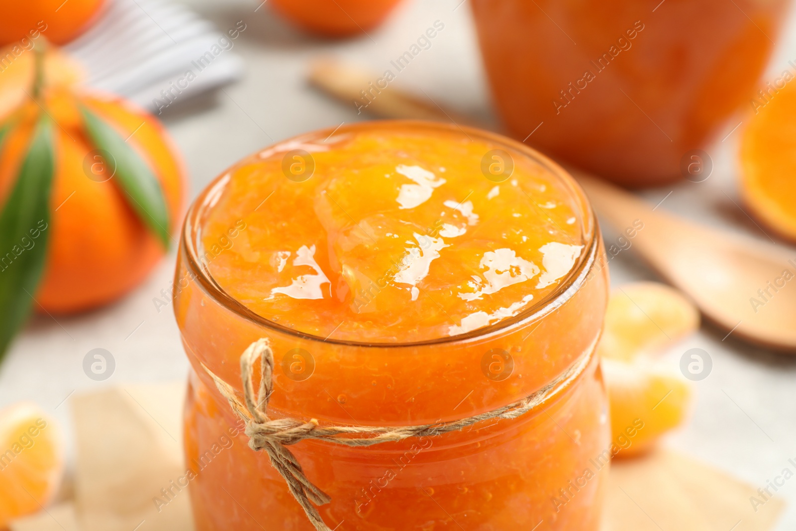 Photo of Delicious tangerine jam in glass jar, closeup