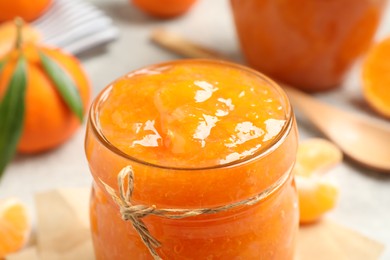 Photo of Delicious tangerine jam in glass jar, closeup