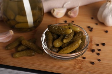 Photo of Tasty pickled cucumbers in glass bowl on wooden table