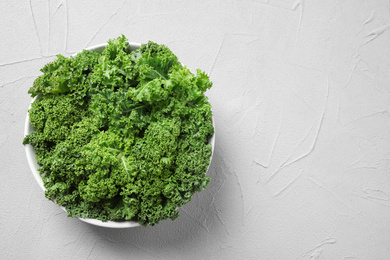 Photo of Fresh kale leaves on white table, top view. Space for text