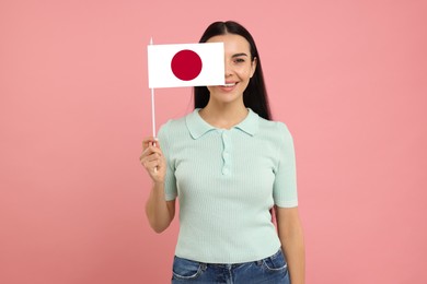 Happy young woman with flag of Japan on pink background