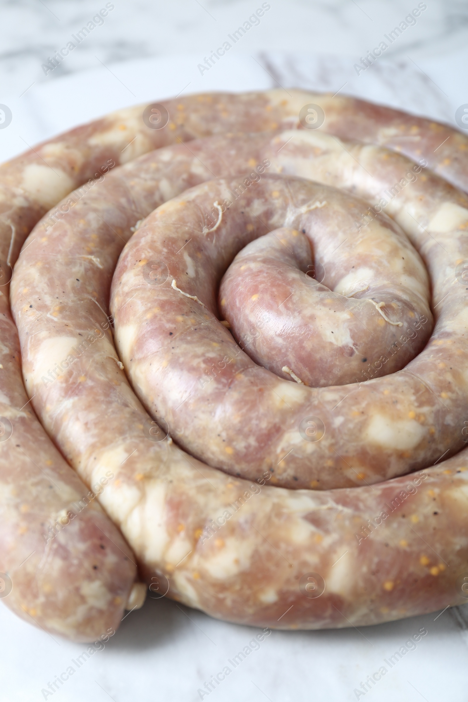 Photo of Raw homemade sausage on white marble table, closeup