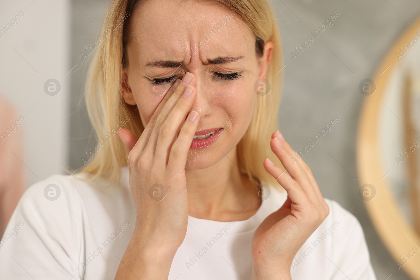 Photo of Sad woman with smeared mascara crying indoors, closeup