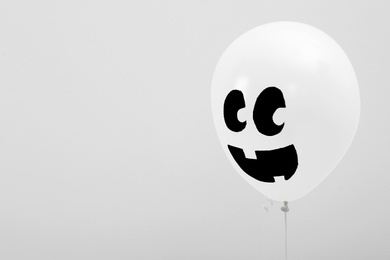 Photo of Balloon with drawing of happy face on light background, space for text. Halloween party