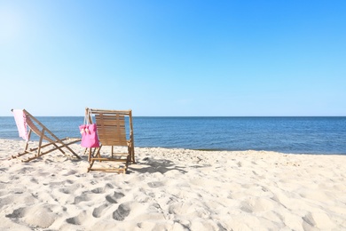 Empty wooden sunbeds and beach accessories on sandy shore