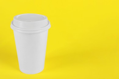 Photo of Paper cup with plastic lid on yellow background, space for text. Coffee to go