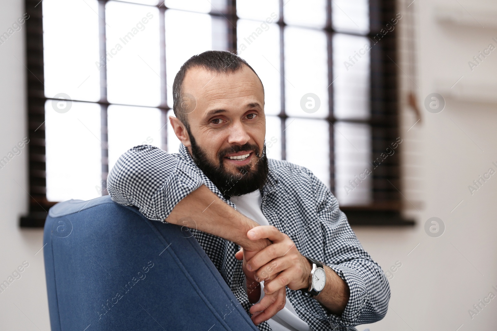 Photo of Portrait of handsome mature man sitting in armchair at home