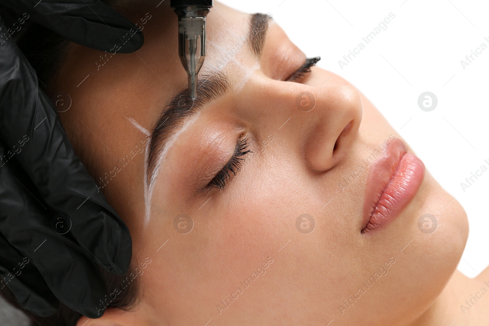 Photo of Beautician making permanent eyebrow makeup to young woman on white background, closeup
