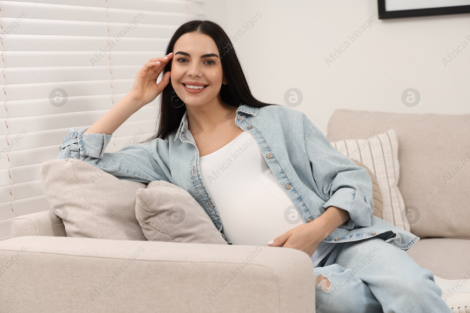 Photo of Happy pregnant woman on sofa at home