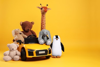 Photo of Child's electric car with other toys on yellow background. Space for text