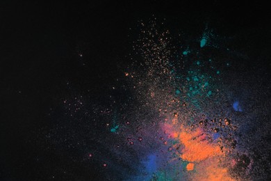 Photo of Colorful powder dyes on dark background, top view with space for text. Holi festival