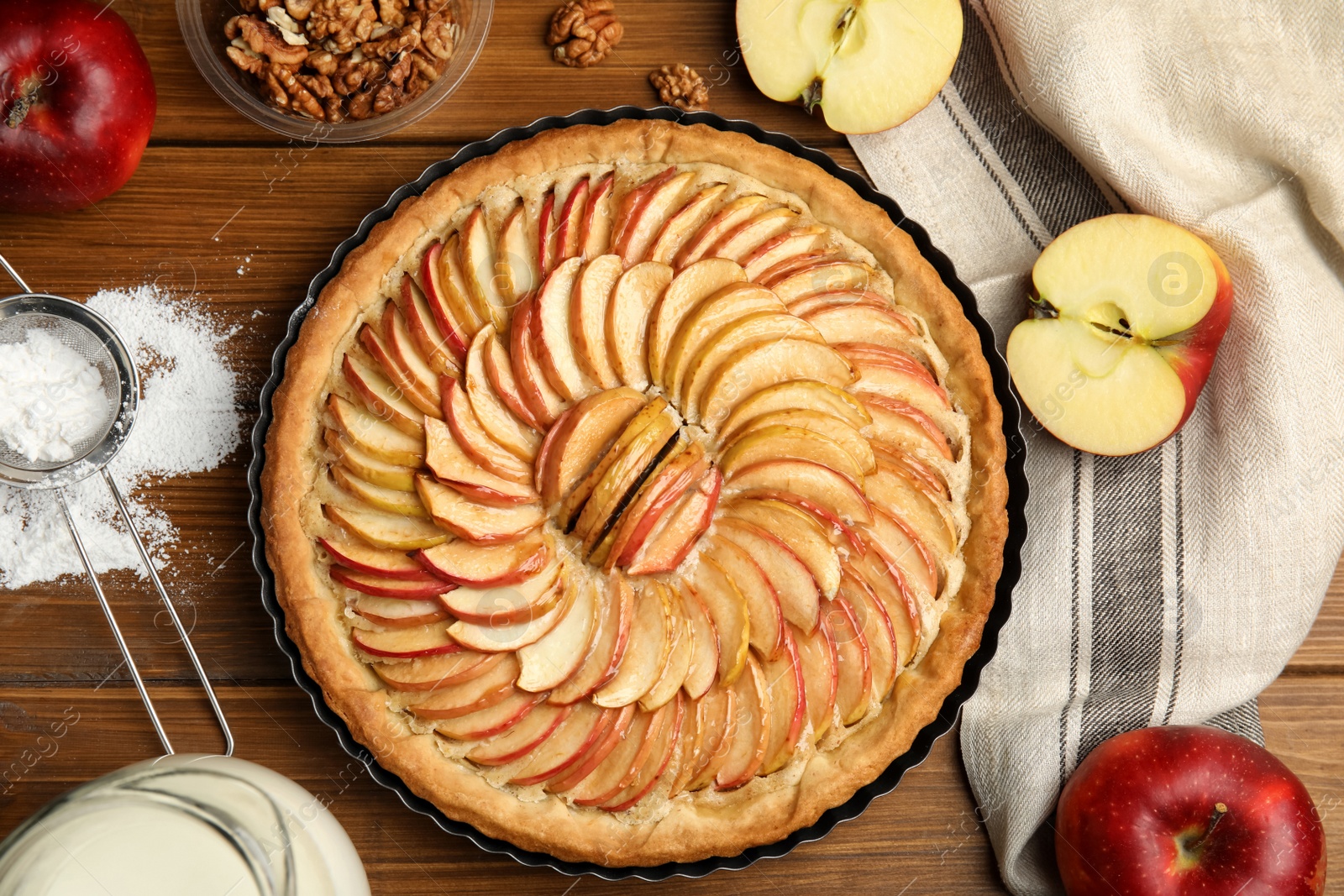 Photo of Delicious homemade apple tart and ingredients on wooden table, flat lay