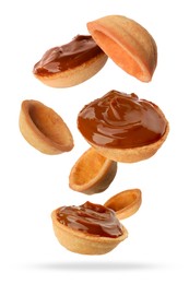 Image of Many empty and filled with caramelized condensed milk nut shell shaped cookie parts falling on white background