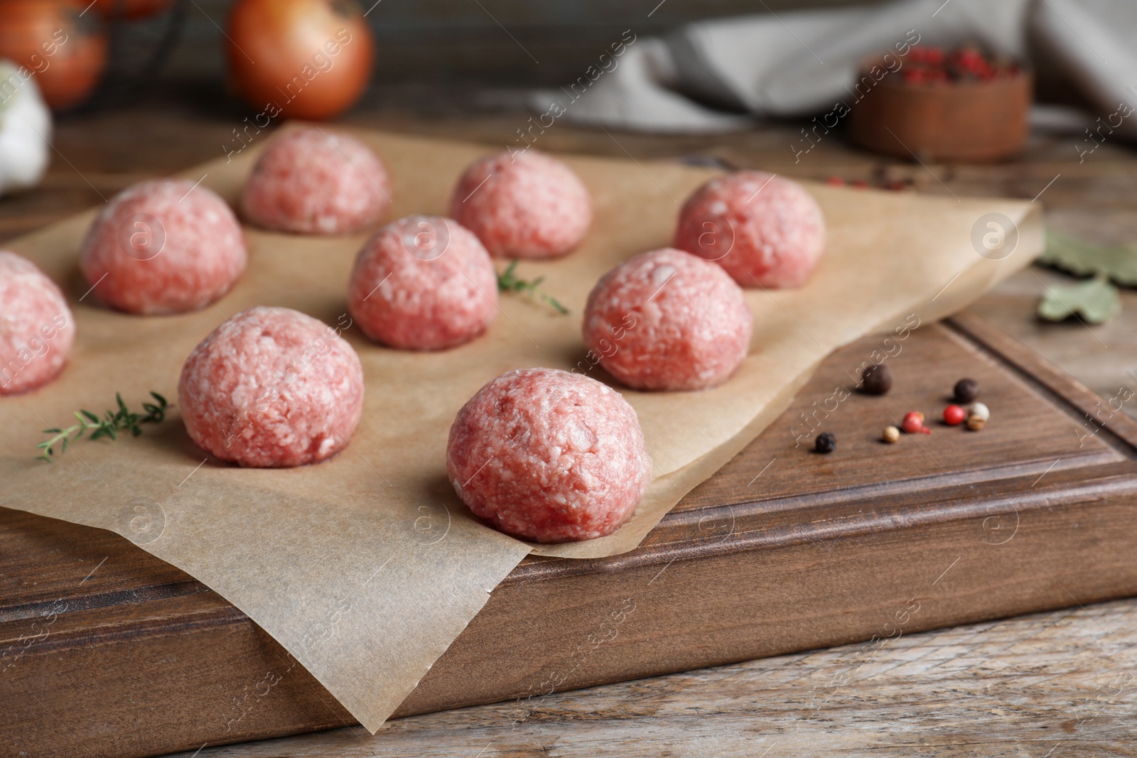 Photo of Many fresh raw meatballs on wooden board, closeup