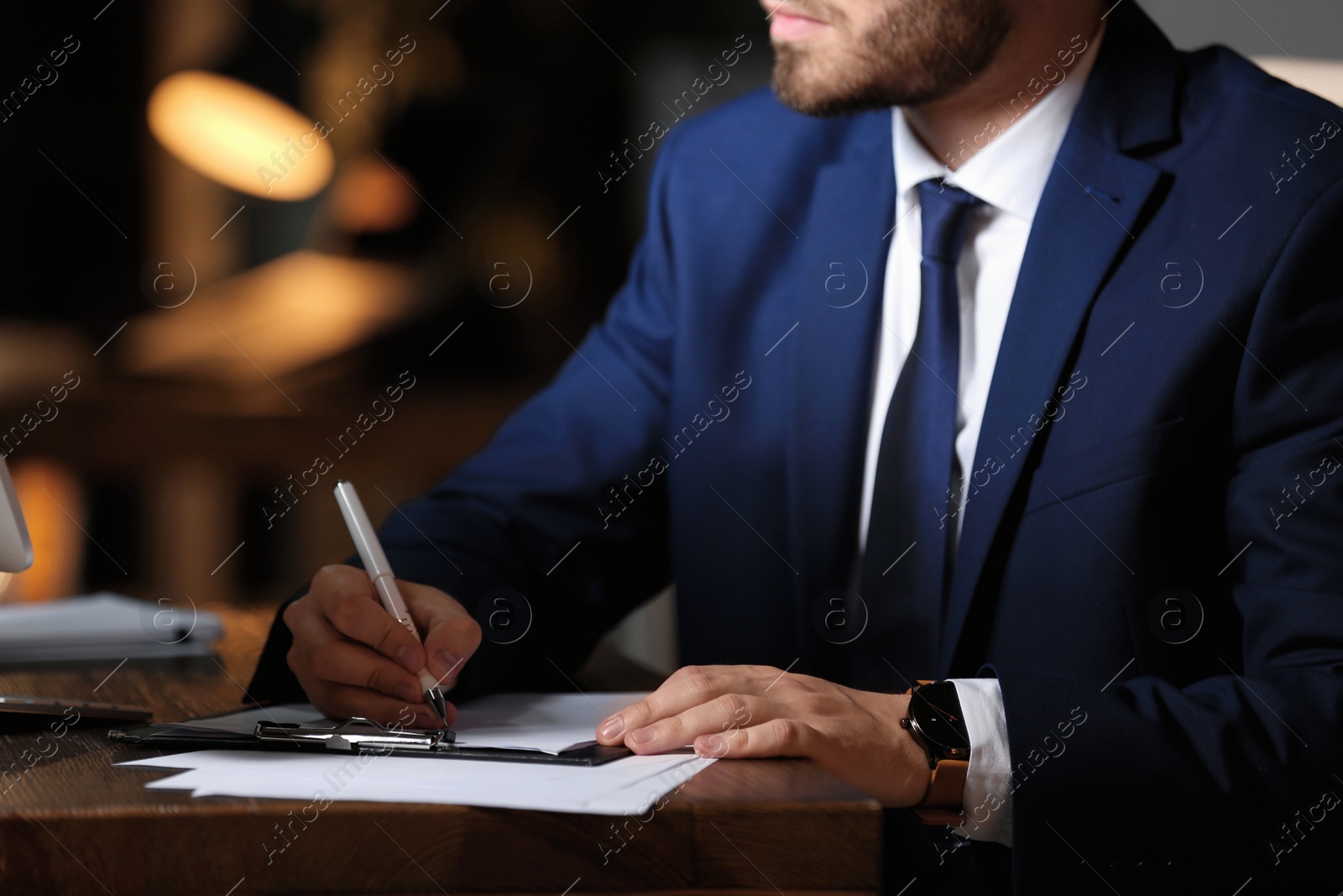 Photo of Young businessman working in office alone at night, closeup