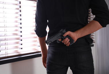 Photo of Man with gun near window indoors, closeup
