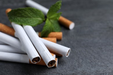 Photo of Menthol cigarettes and mint on grey table, closeup. Space for text