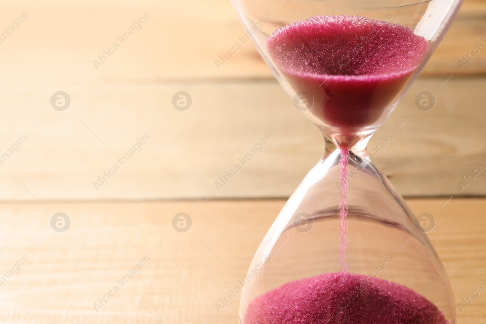 Photo of Hourglass with flowing sand on table, closeup. Time management