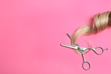 Photo of Hair lock and scissors on color background, top view with space for text