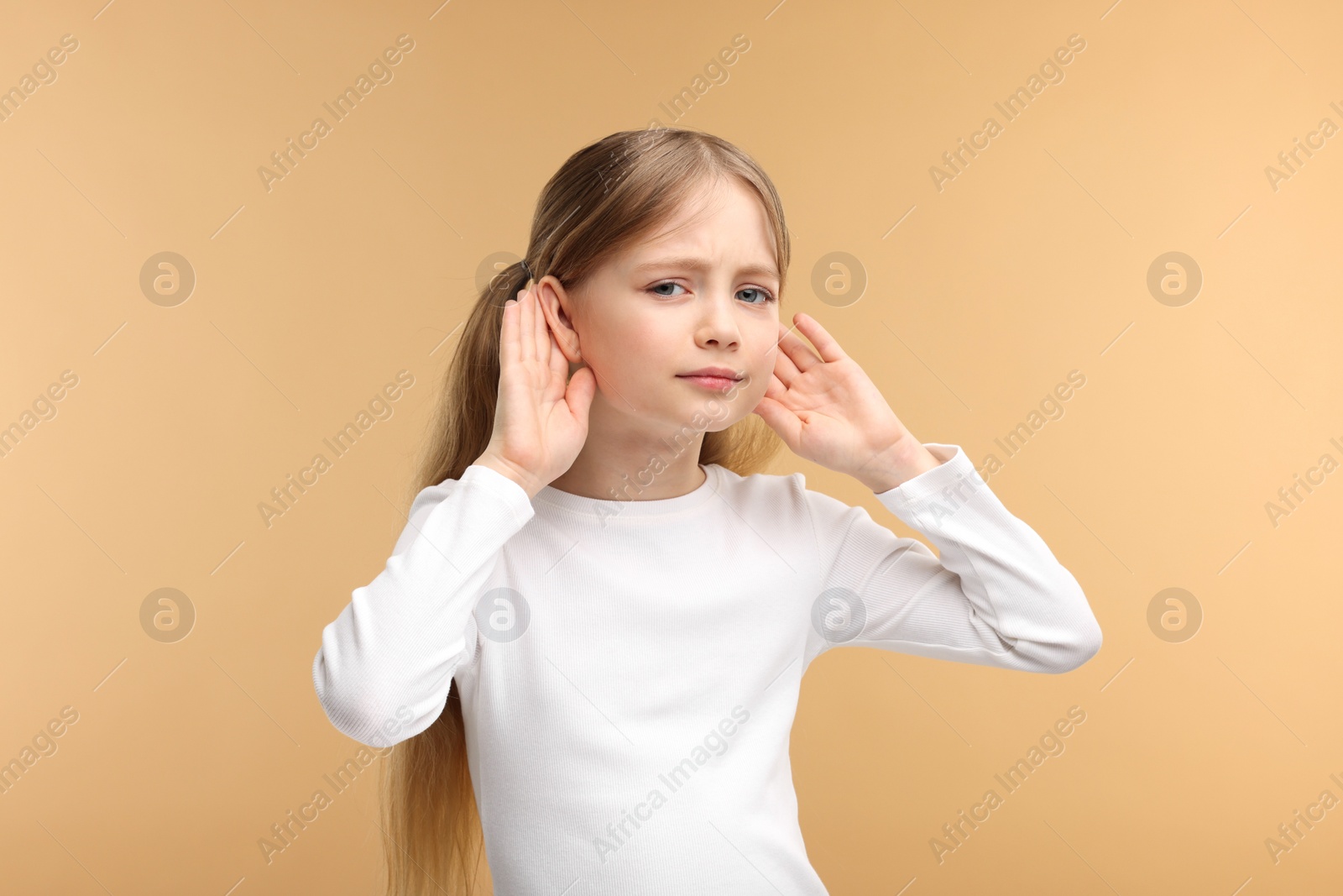 Photo of Little girl with hearing problem on pale brown background