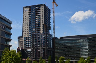 Photo of Tower crane near unfinished buildings against blue sky