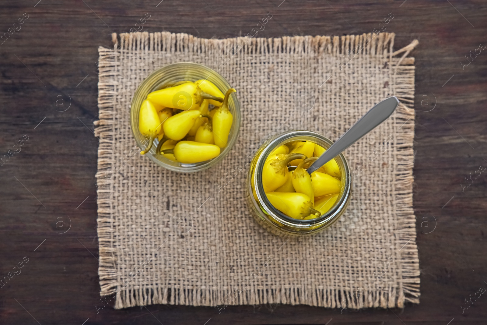 Photo of Pickled yellow jalapeno peppers on wooden table, top view