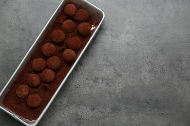 Delicious chocolate candies powdered with cocoa on grey table, top view. Space for text