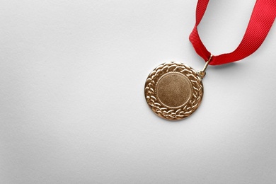 Photo of Gold medal on white background, top view with space for text. Symbol of victory