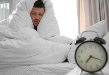 Photo of Sleepy man with cover at home in morning