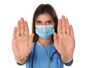 Photo of Doctor in protective mask showing stop gesture on white background. Prevent spreading of coronavirus