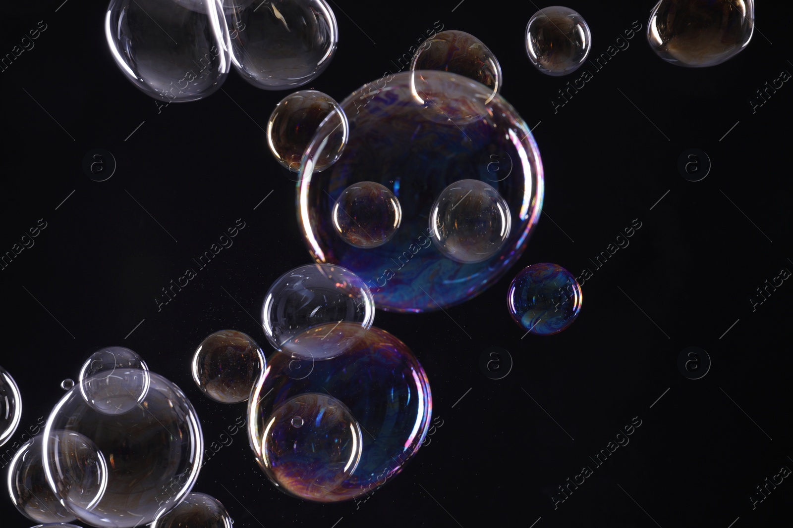 Photo of Many beautiful soap bubbles on black background