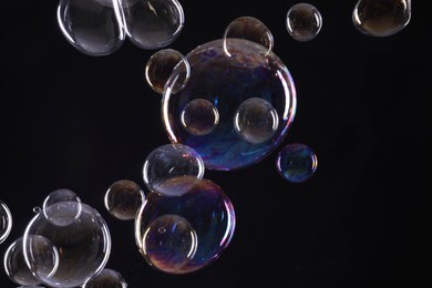 Photo of Many beautiful soap bubbles on black background