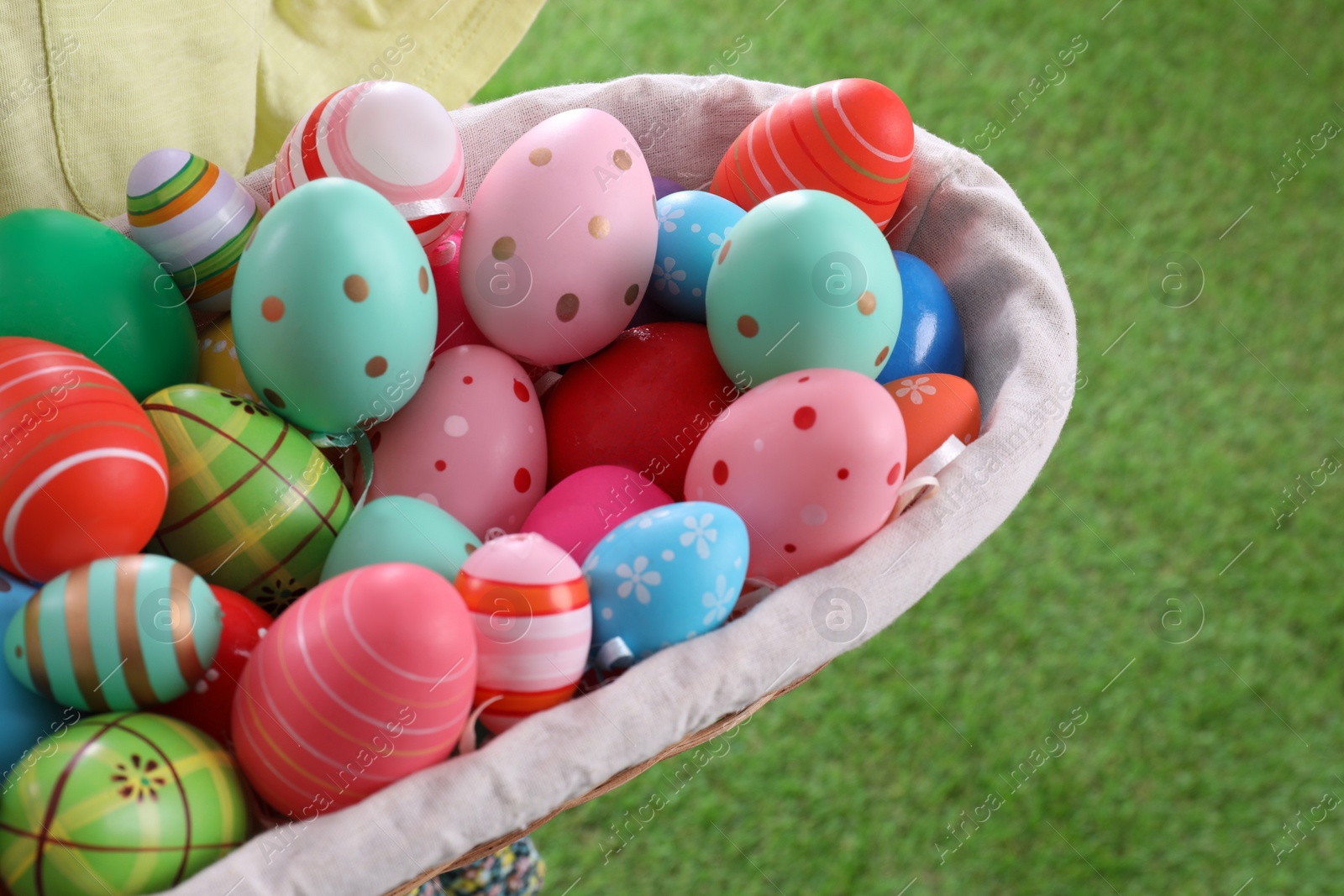 Photo of Child with basket full of Easter eggs outdoors, closeup