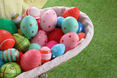 Child with basket full of Easter eggs outdoors, closeup