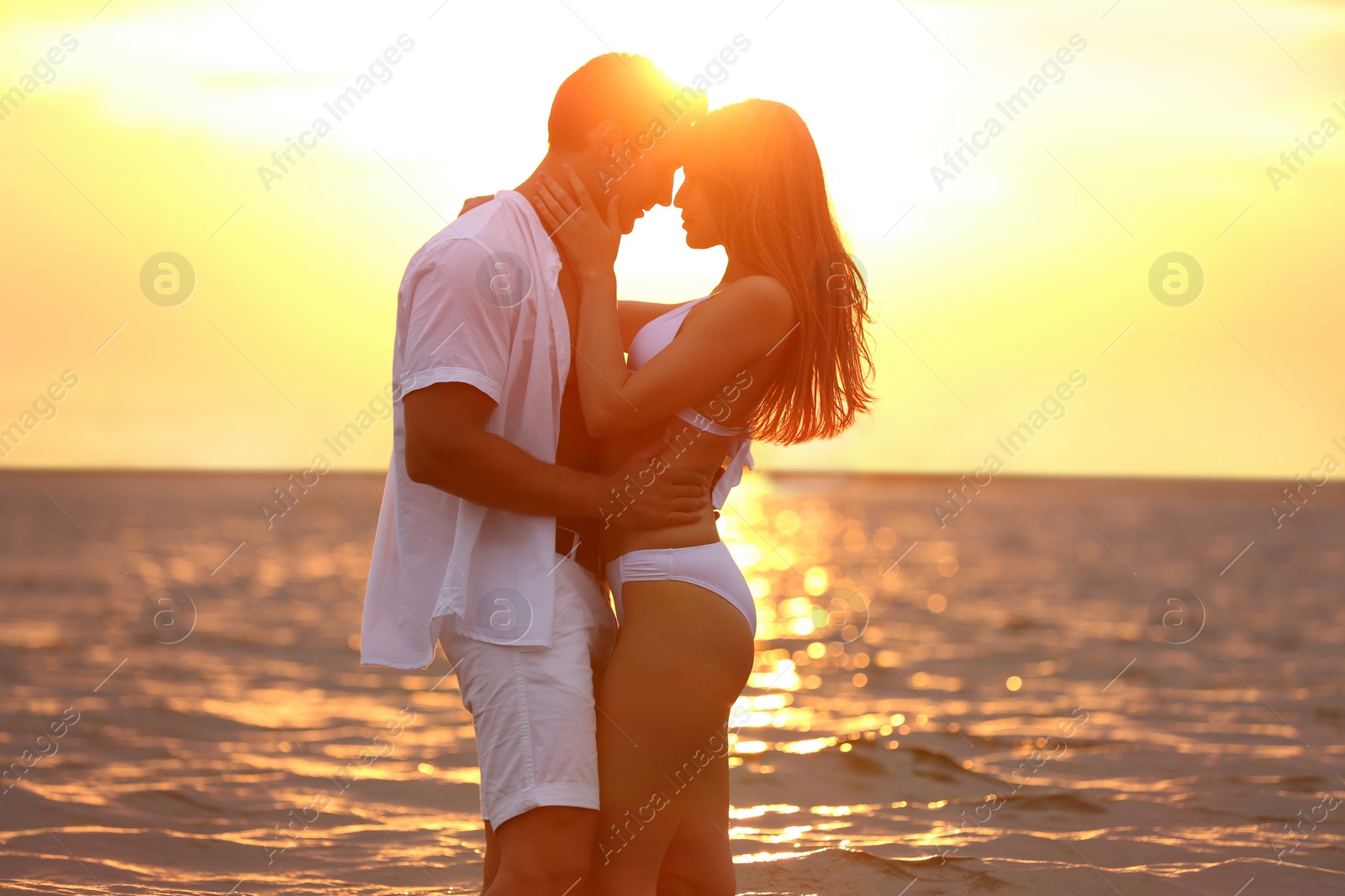 Photo of Happy young couple spending time together on sea beach at sunset