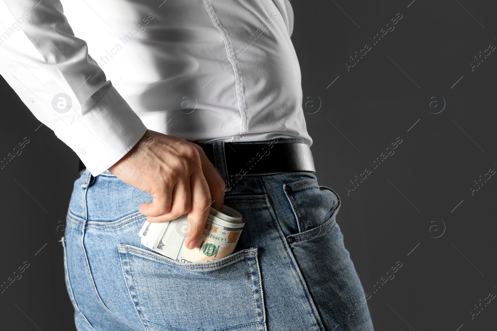 Photo of Man putting bribe money into pocket on black background, closeup