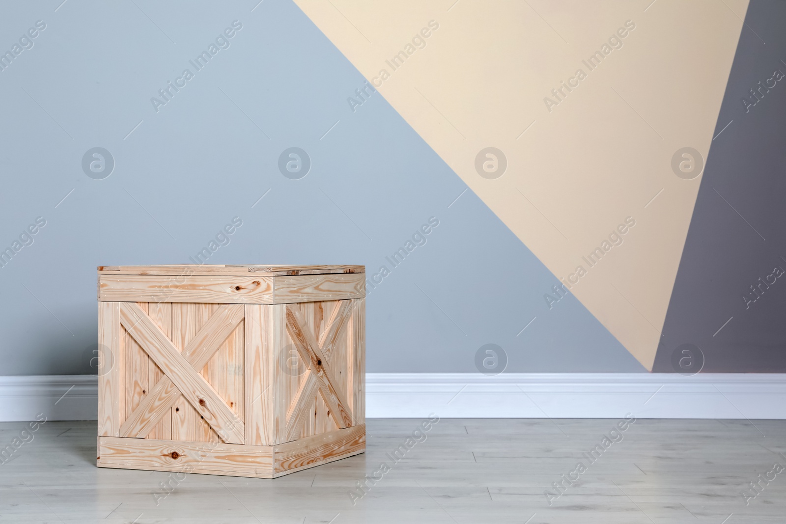 Photo of Wooden crate on floor at color wall. Space for text