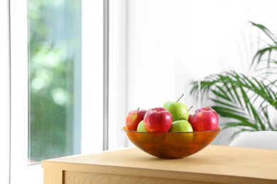 Photo of Bowl of fresh apples on table indoors. Space for text