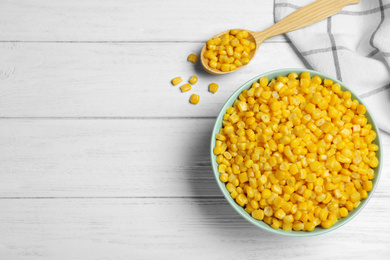 Photo of Delicious canned corn in bowl on white wooden table, flat lay. Space for text