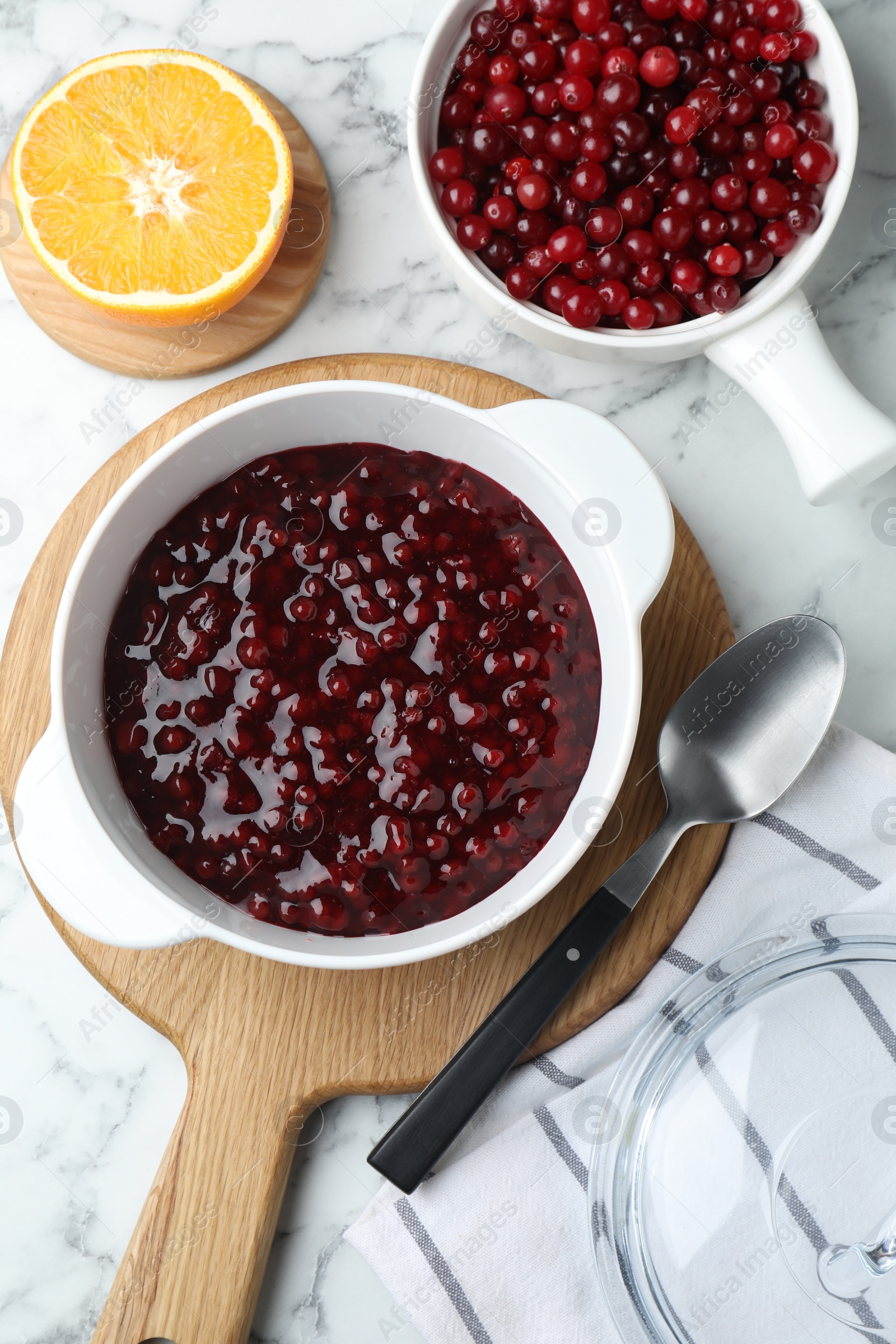 Photo of Fresh cranberry sauce in bowl served on white marble table, flat lay