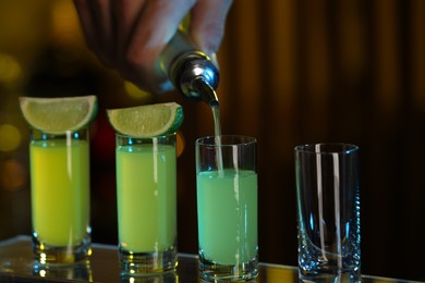 Photo of Bartender pouring alcohol drink into shot glass on blurred background, closeup