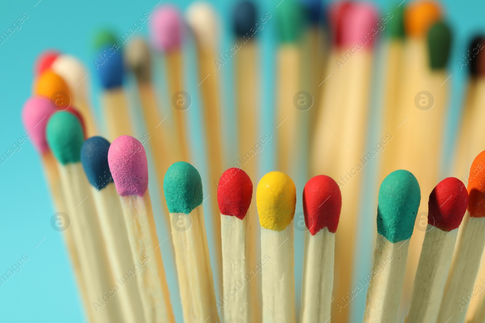 Photo of Matches with colorful heads on light blue background, closeup