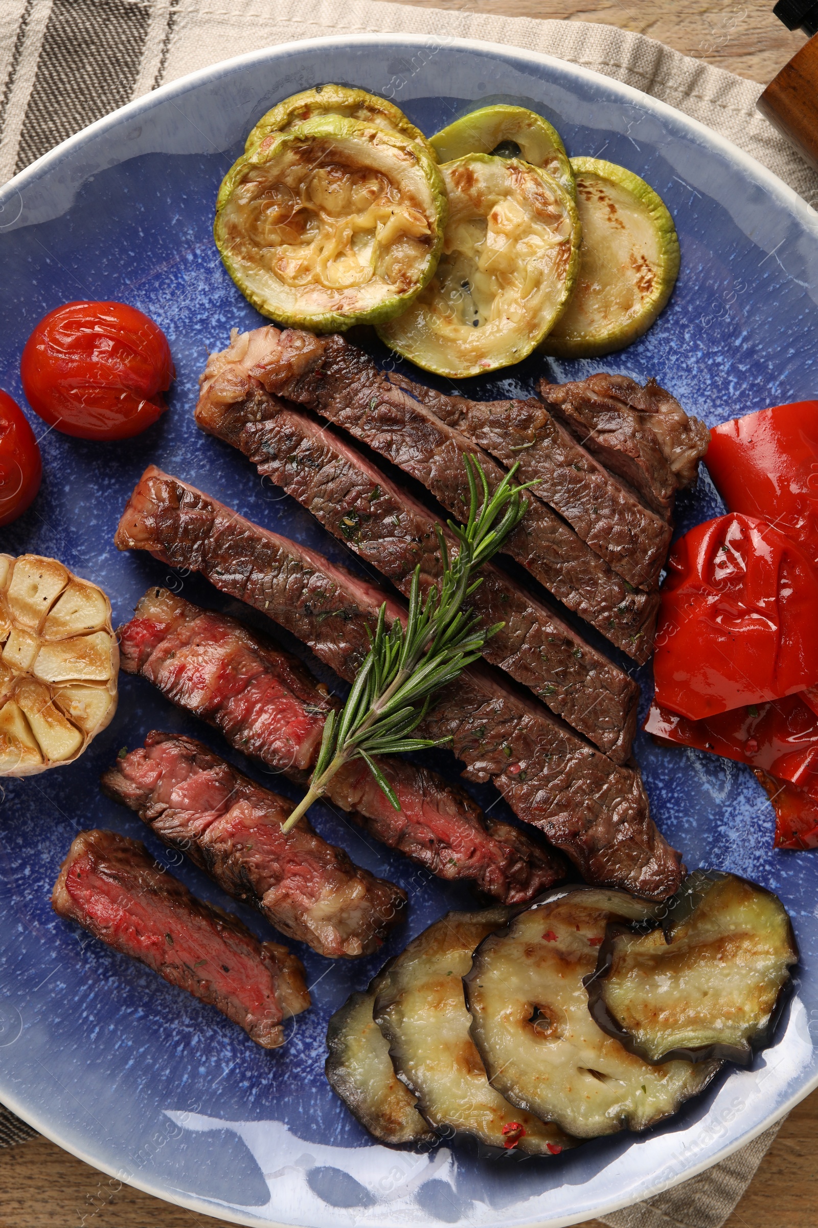 Photo of Delicious grilled beef steak with vegetables and spices on table, top view