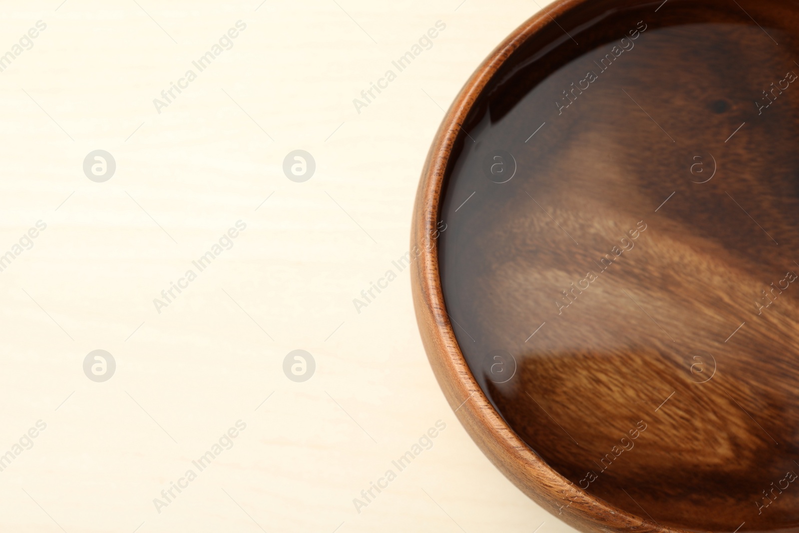Photo of Bowl full of water on wooden table, space for text