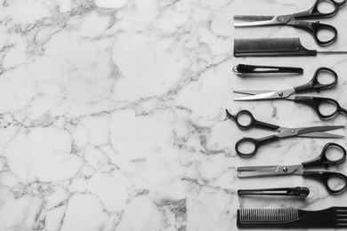 Photo of Flat lay composition with scissors and other hairdresser's accessories on white marble background. Space for text